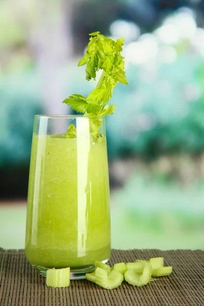 Vaso de jugo de apio, sobre estera de bambú, sobre fondo verde —  Fotos de Stock