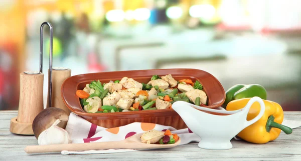 Braadpan met groenten en vlees, op houten tafel, op lichte achtergrond — Stockfoto