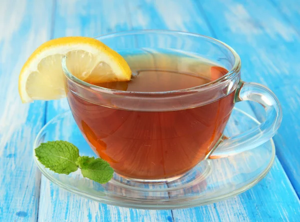 Kopp te med citron på bordet på blå bakgrund — Stockfoto