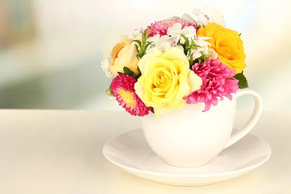 Belo buquê de flores brilhantes na caneca de cor, na mesa de madeira, no fundo claro — Fotografia de Stock