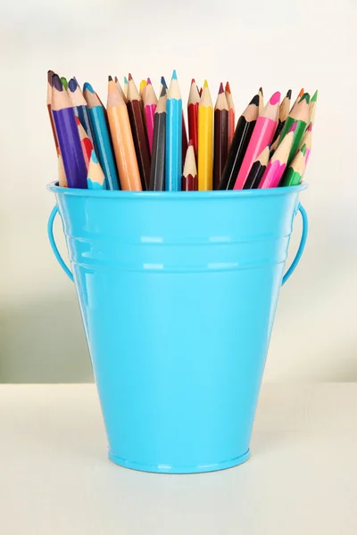 Seau couleur avec crayons multicolores, sur fond de couleur — Photo
