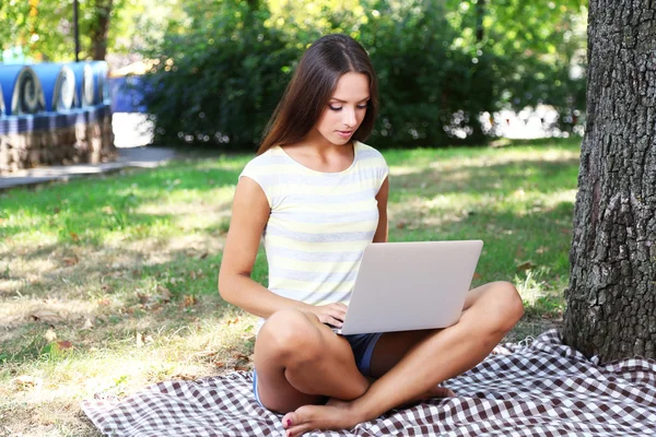 Beautiful young girl with laptop in park — Stock Photo, Image