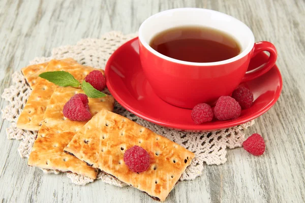 Kopje thee met koekjes en frambozen op tabel close-up — Stockfoto