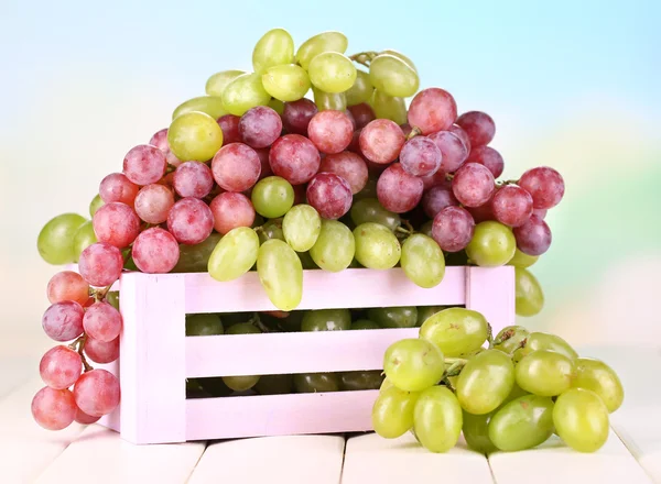 Спелые зеленый и фиолетовый виноград в деревянной коробке на деревянном столе на естественном фоне — стоковое фото