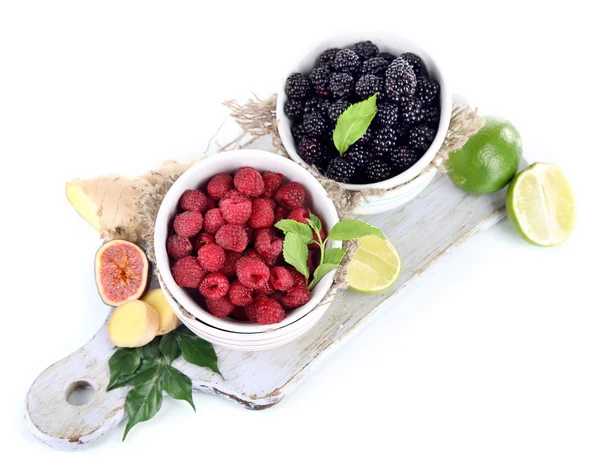 Frambuesas y moras en tazones pequeños a bordo aislados en blanco —  Fotos de Stock