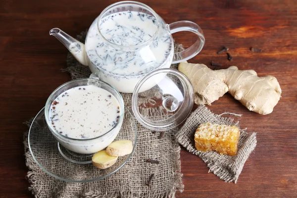 Çaydanlık ve çay süt ve baharatlar üstünde çul ahşap tablo — Stok fotoğraf