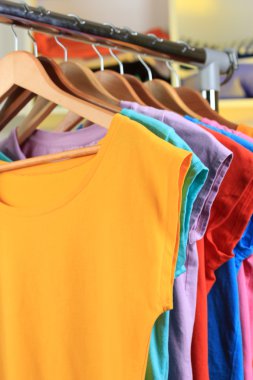 çeşitli ahşap askı raf arka plan üzerinde rahat t-shirt