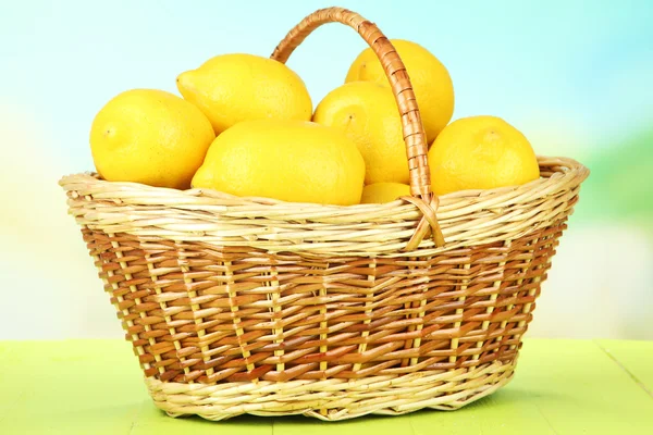Спелые лимоны в плетеной корзине на столе на ярком фоне — стоковое фото
