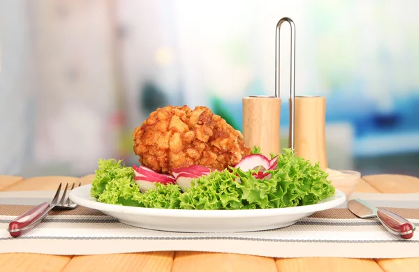 Chicken Kiev on croutons with lettuce salad, on wooden table, on bright background — Stock Photo, Image