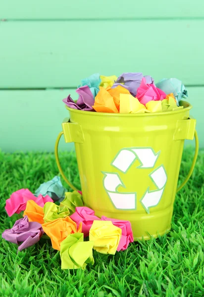 Reciclagem bin na grama verde na cor de fundo de madeira — Fotografia de Stock