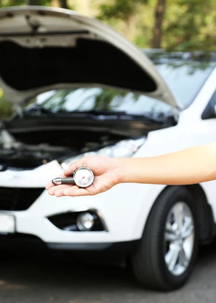 Hand holding pressure gauge for car tyre pressure measurement — Stock Photo, Image