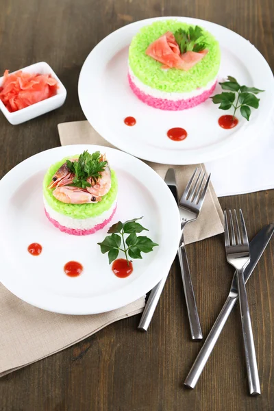 Colored rice on plates on napkins on wooden table — Stock Photo, Image