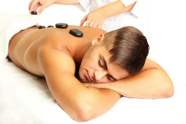 Giovane uomo con massaggio di pietra nel salone spa — Foto Stock