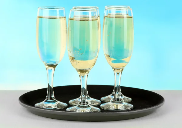 Many glasses of champagne on the tray on table, on blue background — Stock Photo, Image