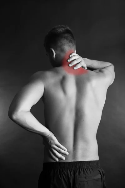 Jovem com dor nas costas em fundo cinza — Fotografia de Stock