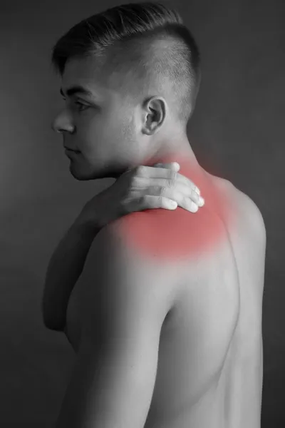 Mladý muž s bolesti šíje na šedém pozadí — Stock fotografie