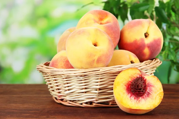 Ripe sweet peaches in wicker basket, on bright background