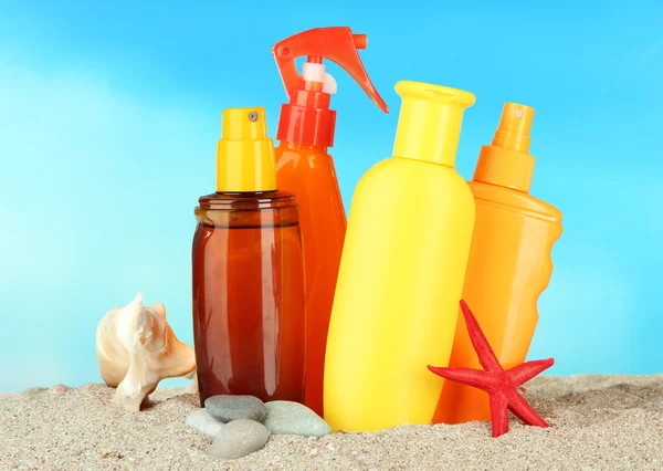 Bottles with suntan cream, on blue background — Stock Photo, Image