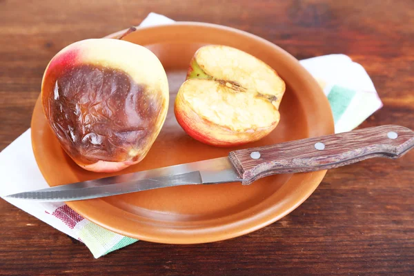 Гнилые яблоки на тарелке на столе — стоковое фото