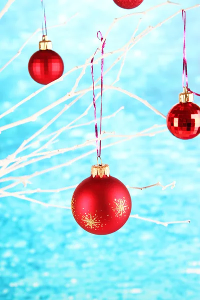 Juguetes de Navidad colgando en la rama sobre fondo azul — Foto de Stock