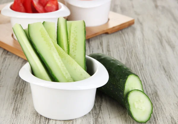 Légumes frais brillants coupés en tranches dans des bols sur une table en bois close-up — Photo