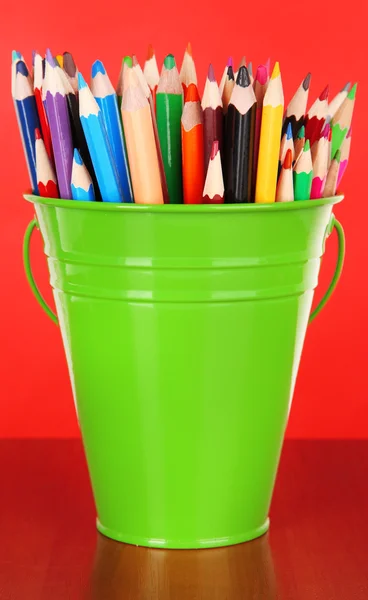 ถังสีที่มีดินสอหลายสี บนพื้นหลังสี — ภาพถ่ายสต็อก