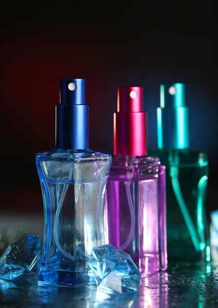 Kvinder parfume i smukke flasker på mørk baggrund med farve lys - Stock-foto