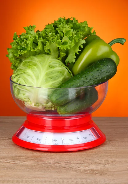 Fresh vegetables in scales on table on orange background — Stock Photo, Image