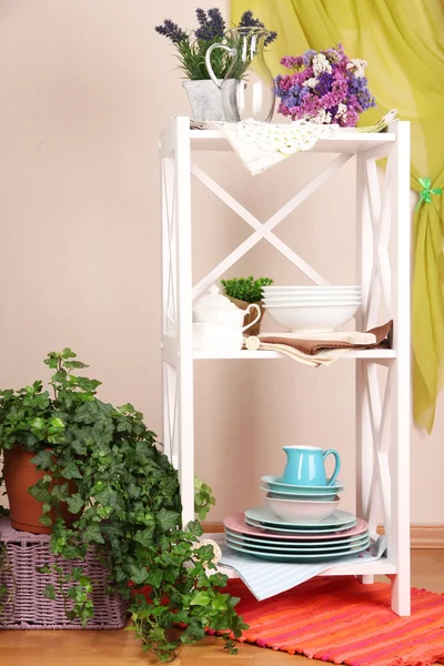 Hermosos estantes blancos con vajilla y decoración, sobre fondo de pared de color — Foto de Stock