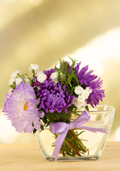 Bellissimo bouquet di fiori brillanti in vaso di vetro, su tavolo di legno, su sfondo luminoso — Foto Stock