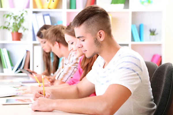 Grupo de jóvenes estudiantes sentados en la biblioteca — Foto de Stock