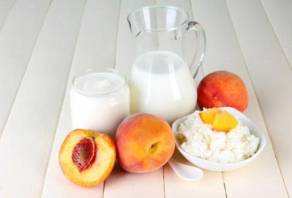 Frische Milchprodukte mit Pfirsichen auf Holztisch in Großaufnahme — Stockfoto