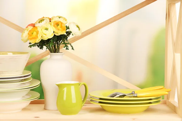 Beautiful dishes on wooden shelf on bright background — Stock Photo, Image