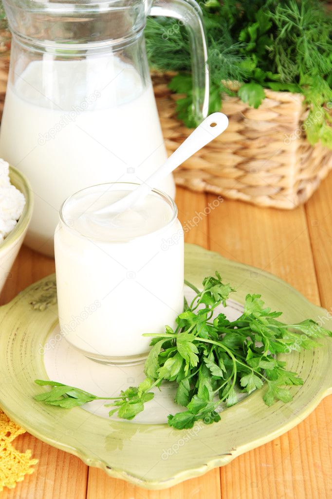 Fresh yogurt with greens on wooden table on natural background