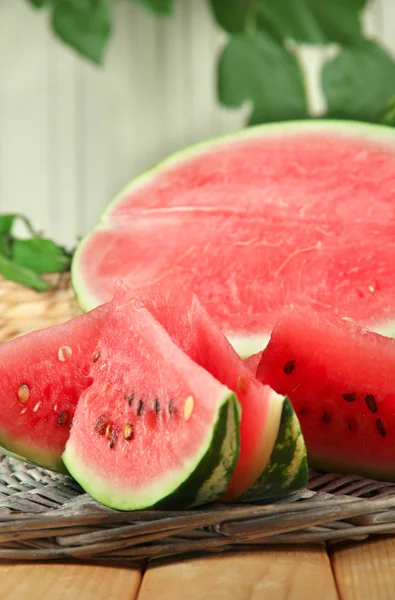 Ripe watermelons on wicker tray on table on wooden background — Stock Photo, Image