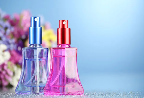Женщины духи в красивых бутылках и цветы на голубом фоне — стоковое фото