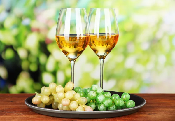 Vyzrálé hrozny a sklenice vína, na světlé pozadí — Stock fotografie