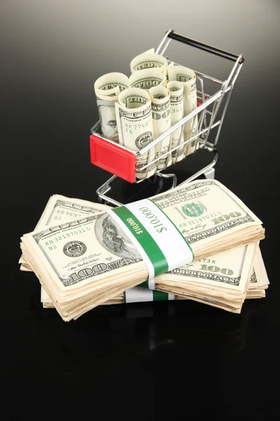 Shopping trolley with dollars, on dark background — Stock Photo, Image