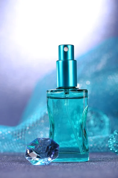 Perfume de mujer en hermosa botella sobre fondo azul — Foto de Stock