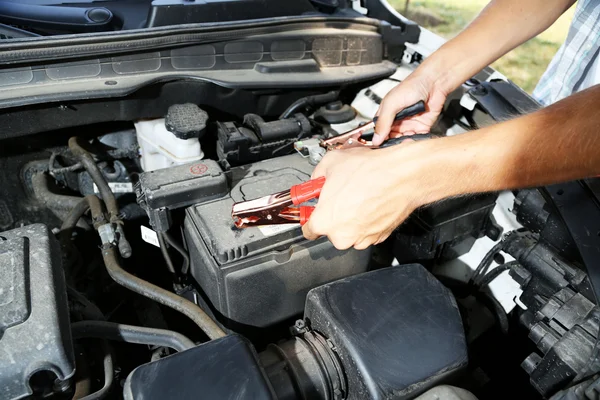 Carro mecânico usa cabos jumper bateria para carregar bateria morta — Fotografia de Stock
