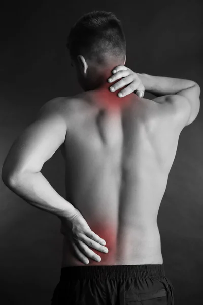 Joven con dolor de espalda sobre fondo gris — Foto de Stock