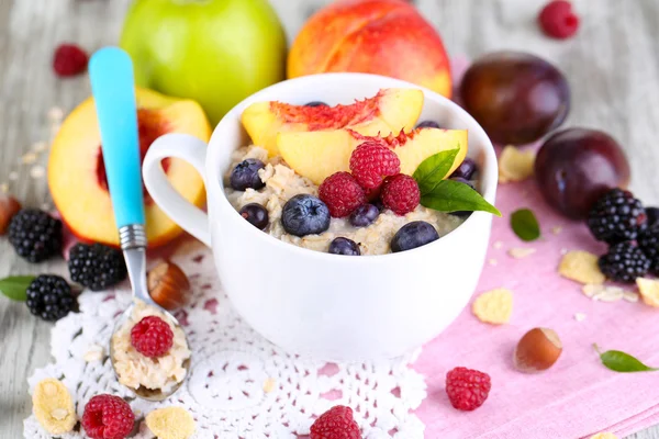 Haferflocken in Tasse mit Beeren auf Servietten auf Holztisch — Stockfoto