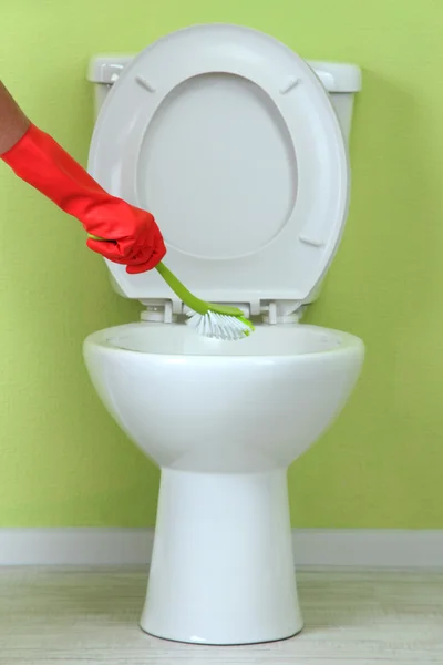 Woman hand with brush cleaning a toilet bowl in a bathroom — Stock Photo, Image