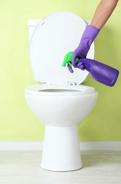 Woman hand with spray bottle cleaning a toilet bowl in a bathroom — Stock Photo, Image