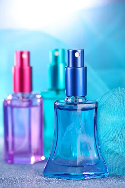 Perfumy kobiety w pięknych butelkach na niebieskim tle — Zdjęcie stockowe