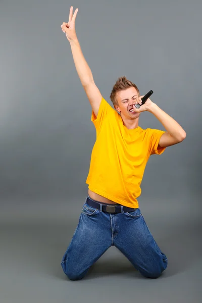Knappe jonge man zingt op grijze achtergrond — Stockfoto