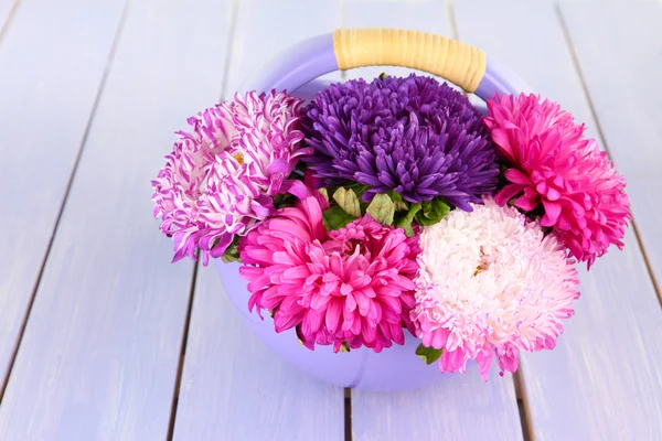 Bright aster flowers in basket on bright wooden background — Stock Photo, Image