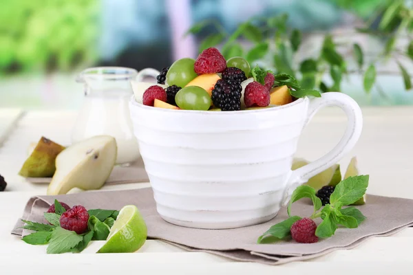 Ensalada de frutas en taza sobre mesa de madera sobre fondo natural —  Fotos de Stock