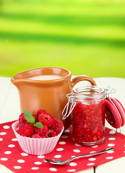Čerstvé maliny, Malinová marmeláda a smetana v džbánu na dřevěný stůl, na světlé pozadí — Stock fotografie