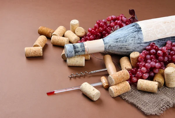 Oude fles wijn, druiven en kurken op bruine achtergrond — Stockfoto